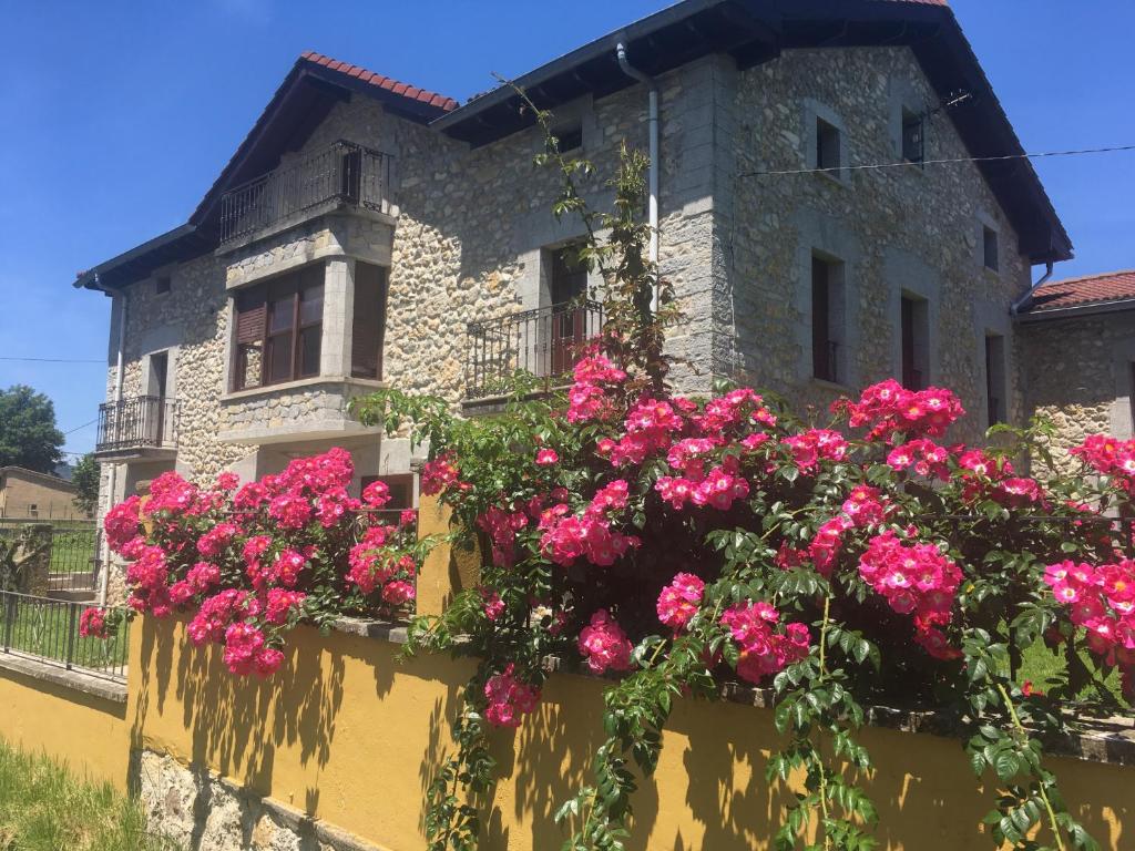 Um edifício com flores cor-de-rosa à frente. em Casa BellaTerra em Villasana de Mena