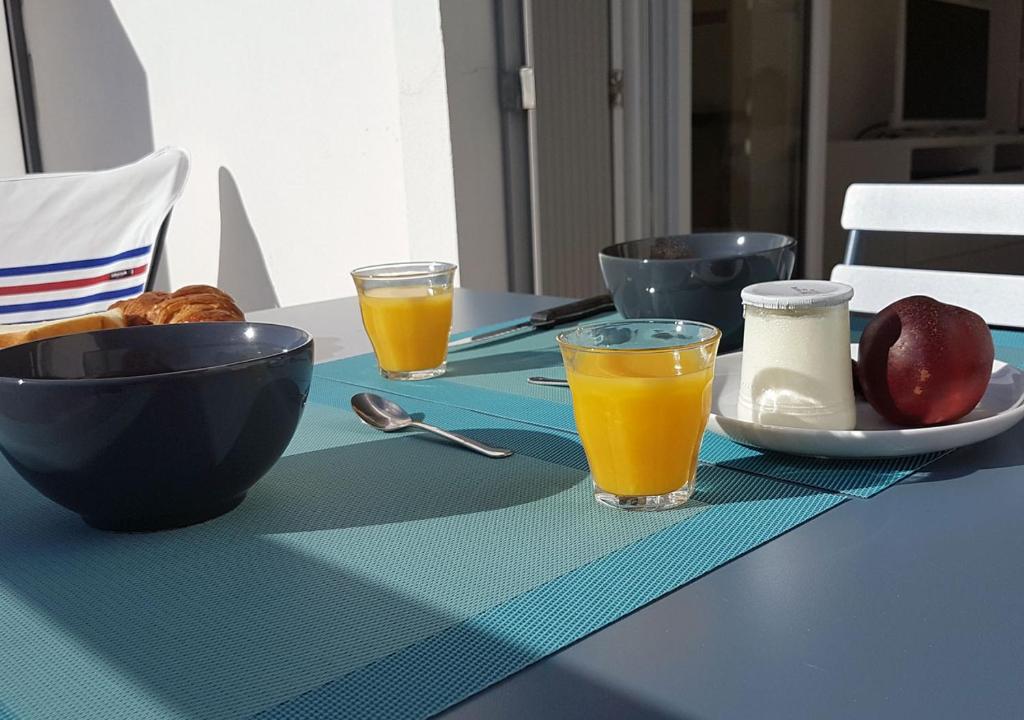 une table avec une assiette de nourriture et deux verres de jus d'orange dans l'établissement Le Rallye Royan, à Royan