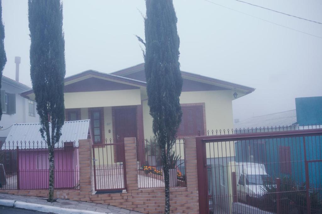 une maison avec une clôture et deux palmiers dans l'établissement Casa Muller, à Gramado