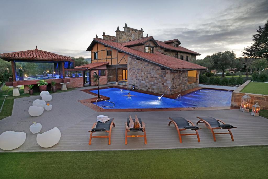 a house with a swimming pool with chairs and a building at Posada Spa San Marcos in Santillana del Mar