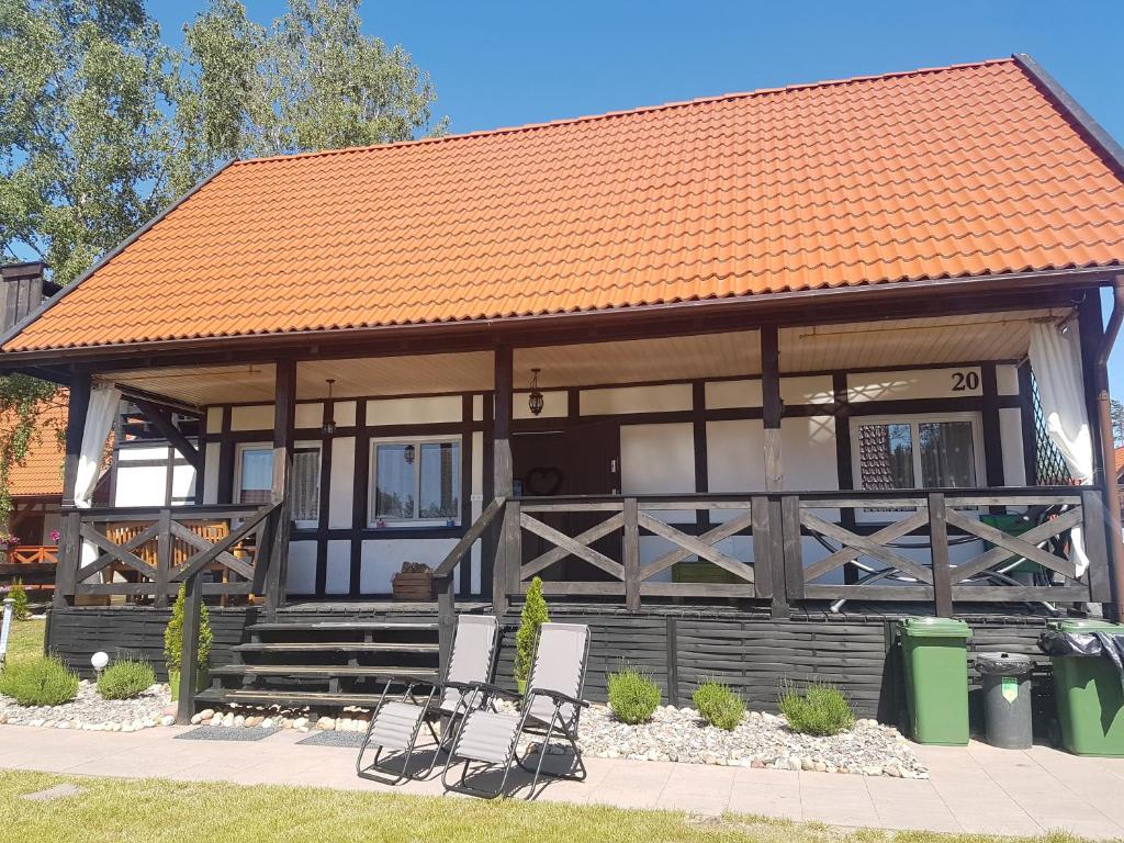 un edificio con techo naranja y sillas delante en Domek 20, en Załakowo