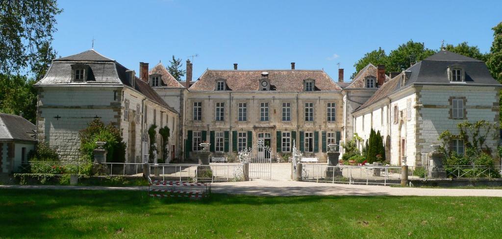 een oud huis met een hek ervoor bij Chateau de Juvigny in Juvigny-sur-Marne