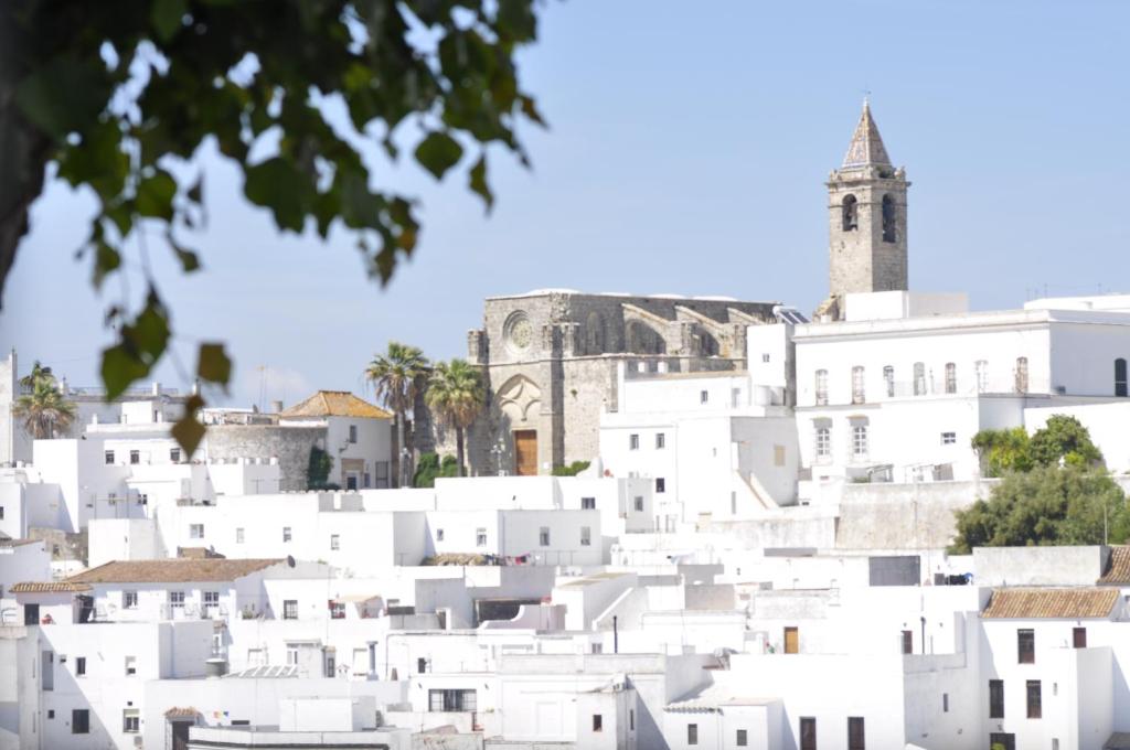 a group of white buildings with a clock tower in the background at Apartamento Los Jardines San Miguel in Vejer de la Frontera