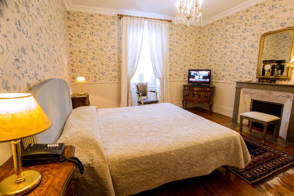 a bedroom with a bed and a fireplace and a television at Hotel La Villa Fleurie in Beaune
