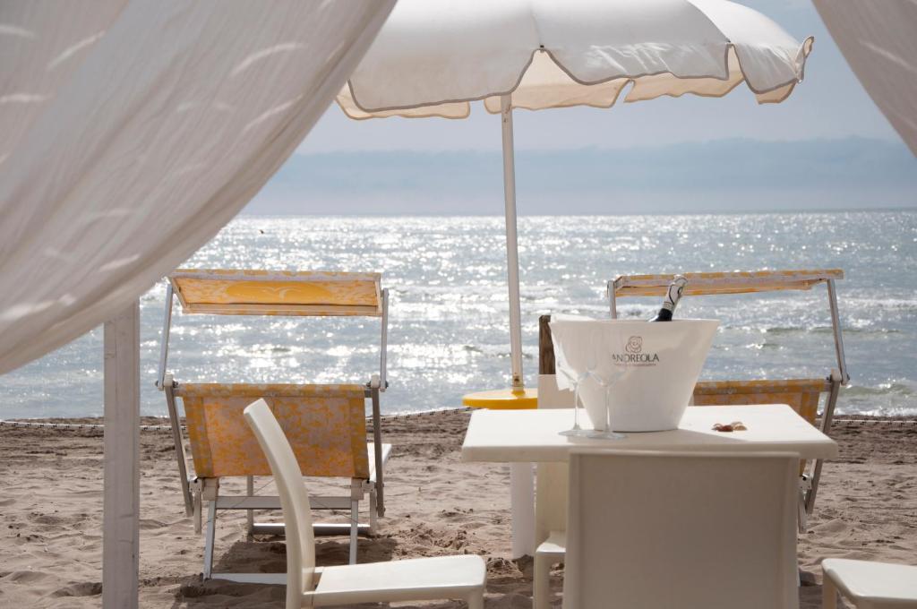 a table and chairs on the beach with an umbrella at Hotel del Mar in Sottomarina