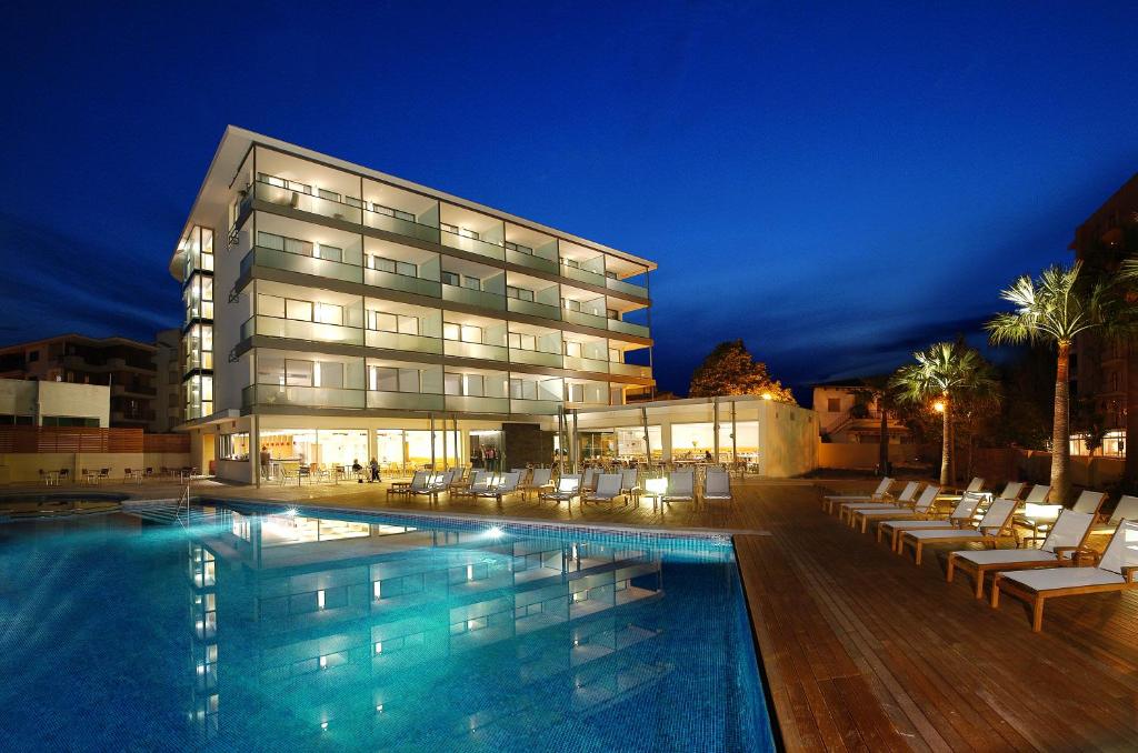 un hotel con piscina di fronte a un edificio di Aimia Hotel a Port de Sóller