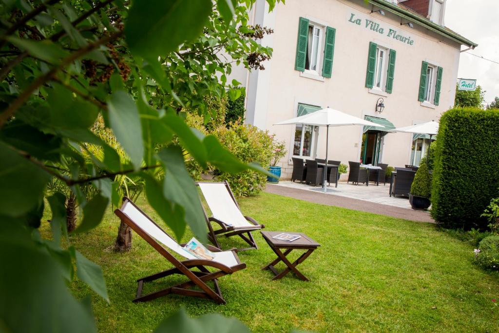 Deux chaises et une table dans l'herbe devant un bâtiment dans l'établissement Hotel La Villa Fleurie, à Beaune