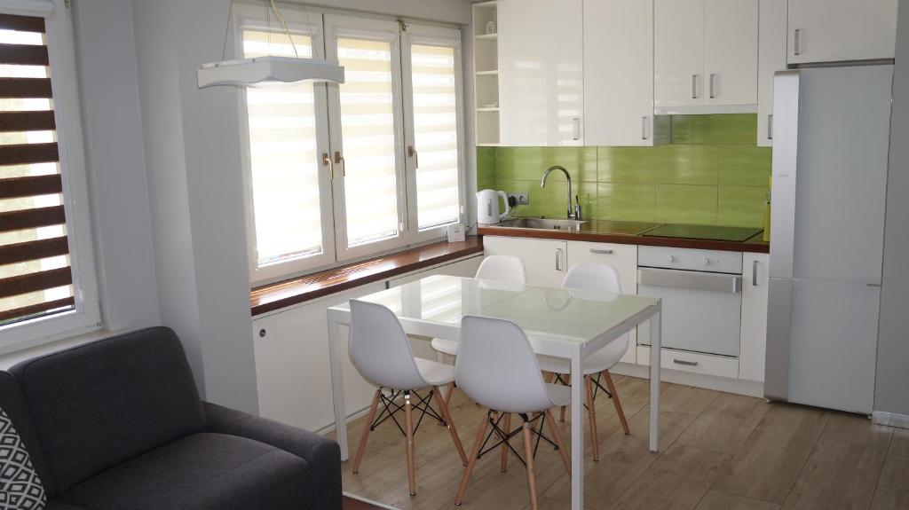 a kitchen with a table and chairs and a couch at APARTAMENT SŁONECZNY in Kołobrzeg