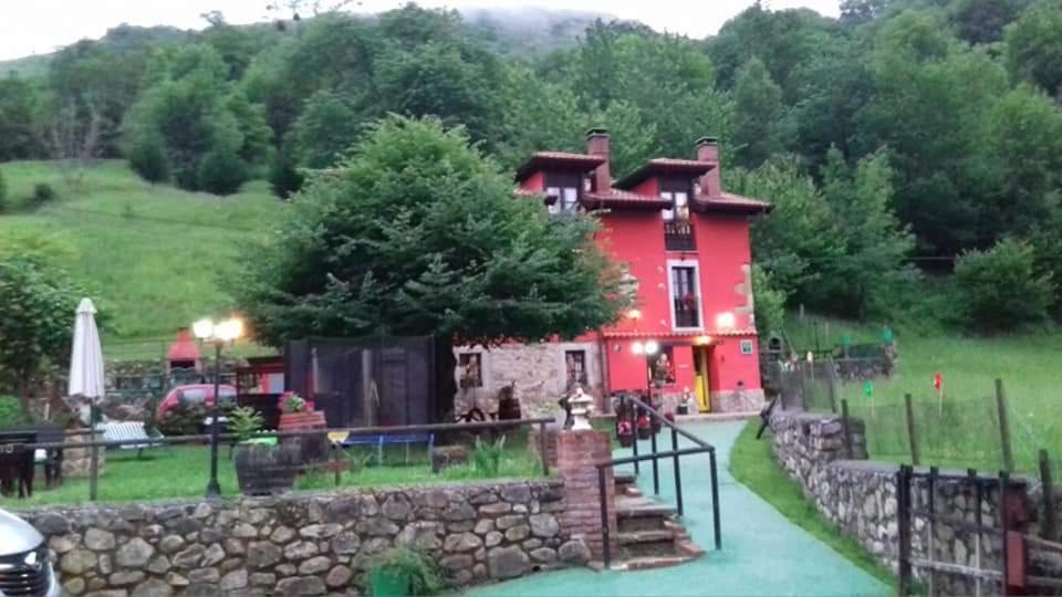 una casa roja con una pared de piedra delante de ella en Apartamentos El Rincon Encantado, en Llano-Con