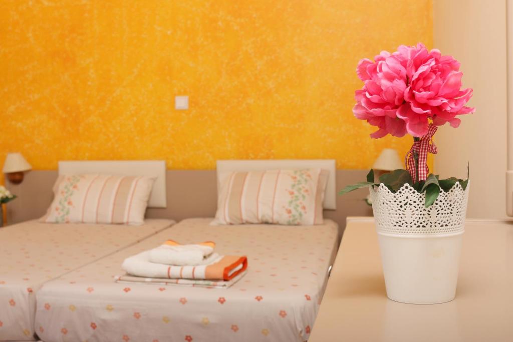 una stanza con due letti e un vaso con un fiore di Corfu View a Perama