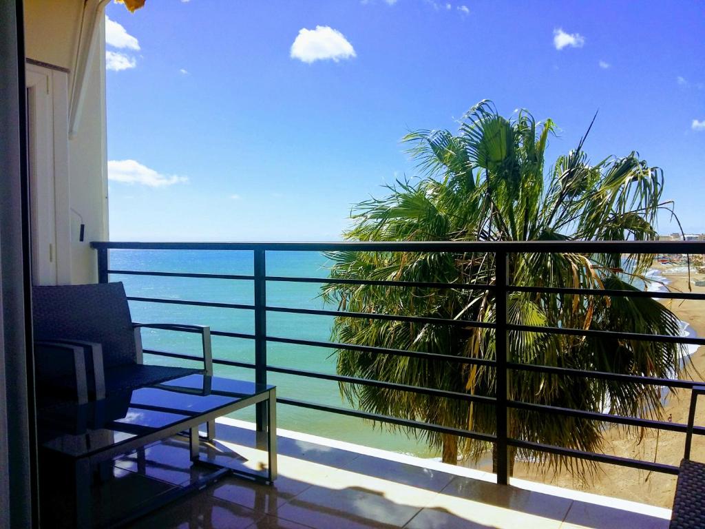 einen Balkon mit Blick auf das Meer und eine Palme in der Unterkunft ESTUDIO EN 1a LINEA in Torremolinos