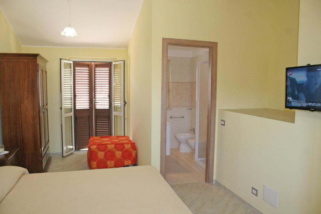 a room with a bed and a television and a bathroom at BB Aretè in Scilla