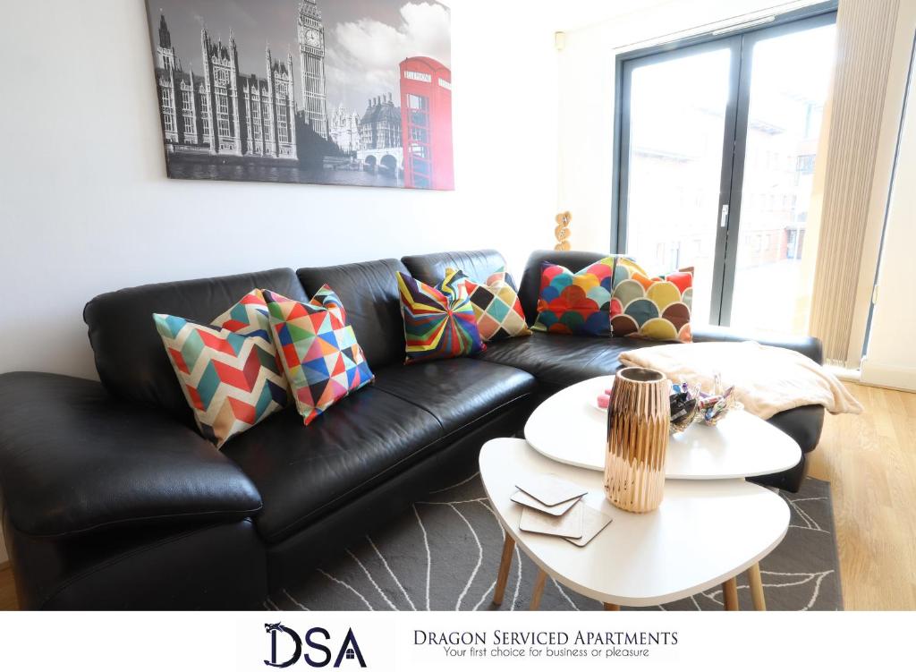 a black leather couch in a living room with a table at Birmingham City Centre Premier Apartment in Birmingham