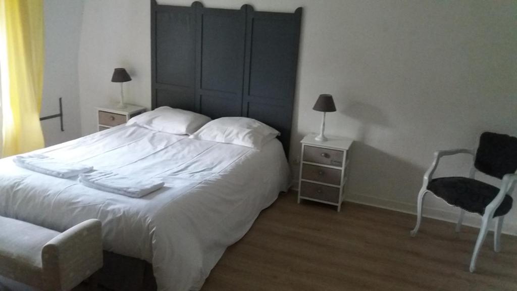una camera con un grande letto bianco e una sedia di Haras De Blingel a Blingel