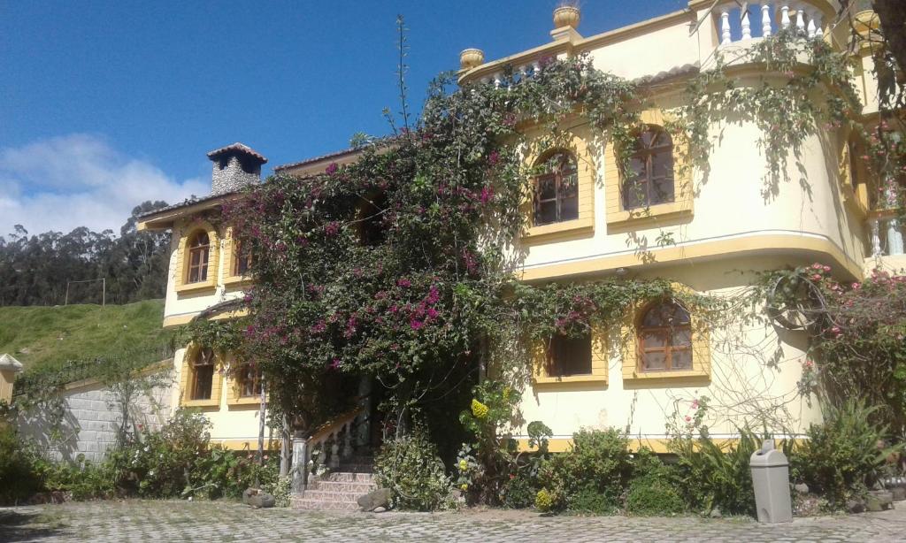a large white building with flowers on it at Hostal Curiñan in Otavalo