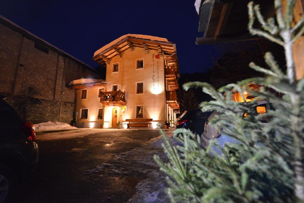 a building at night with a christmas tree in the foreground at Affittacamere Petit Coeur in Champoluc
