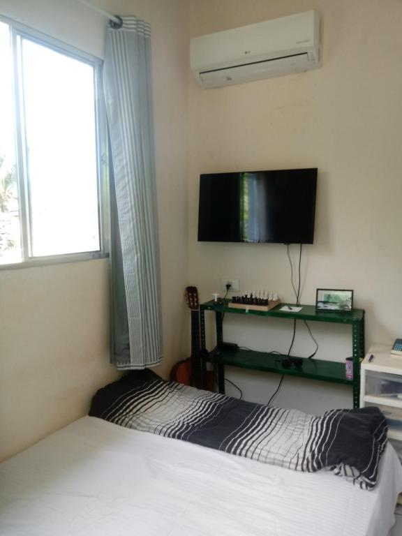 a bedroom with a bed and a flat screen tv at Blue House in Fernando de Noronha