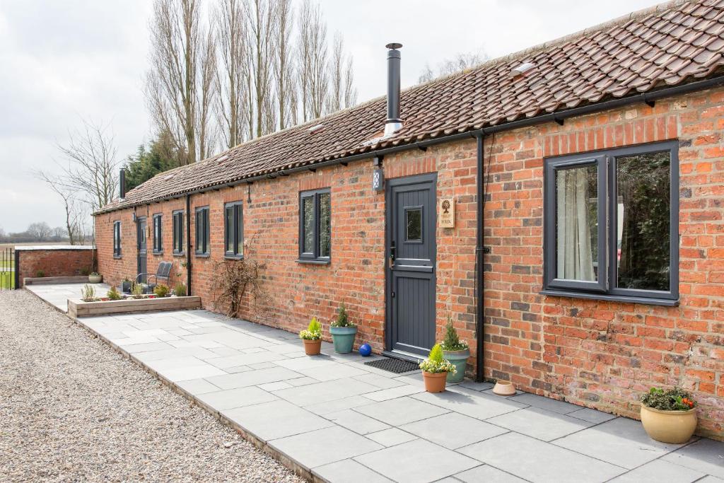 een stenen huis met een zwarte deur en potplanten bij Thrush Nest Cottages - Wren Cottage sleeps 4, 2 bedrooms & Stable Cottage sleeps 2, 1 bedroom in York