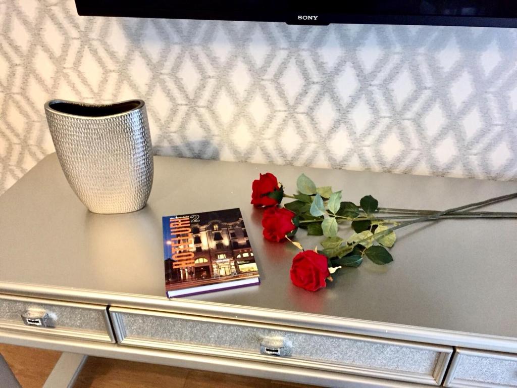 une table avec un vase, un livre et des fleurs dans l'établissement Flori de Iulie Apartamente, à Braşov