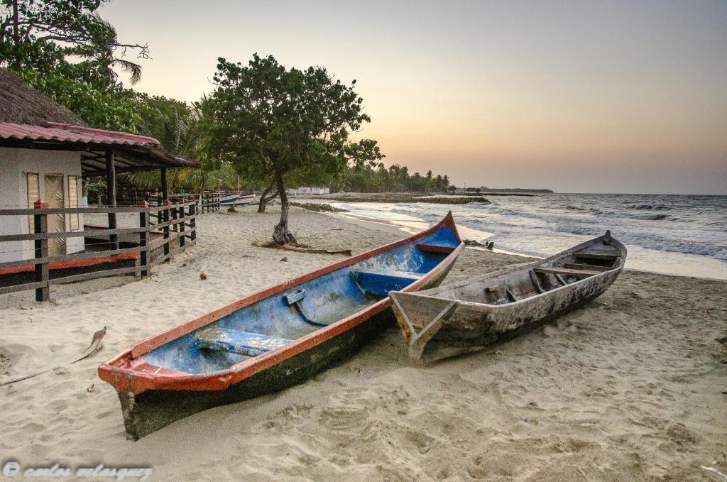 dos barcos sentados en la arena en una playa en Cabañas Los Juanchos Coveñas en Coveñas