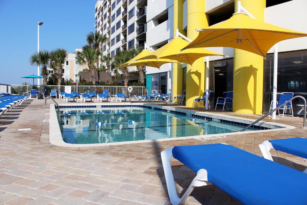 a pool with chairs and umbrellas next to a building at Seaside Resort in Myrtle Beach