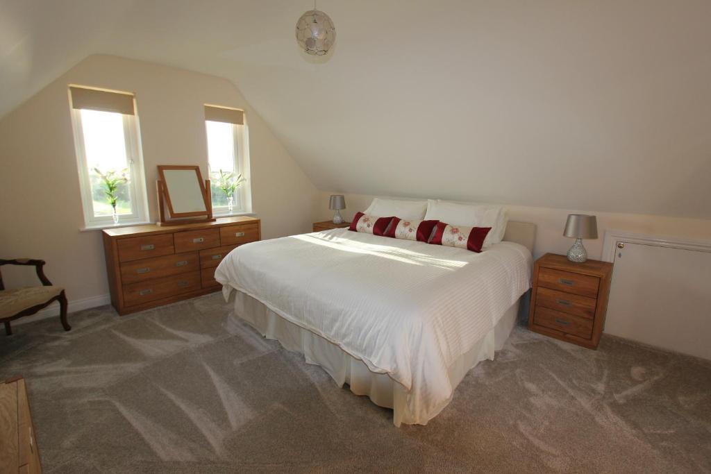 ein Schlafzimmer mit einem großen weißen Bett mit roten Kissen in der Unterkunft Glenside Cottage with Hot Tub in Solva