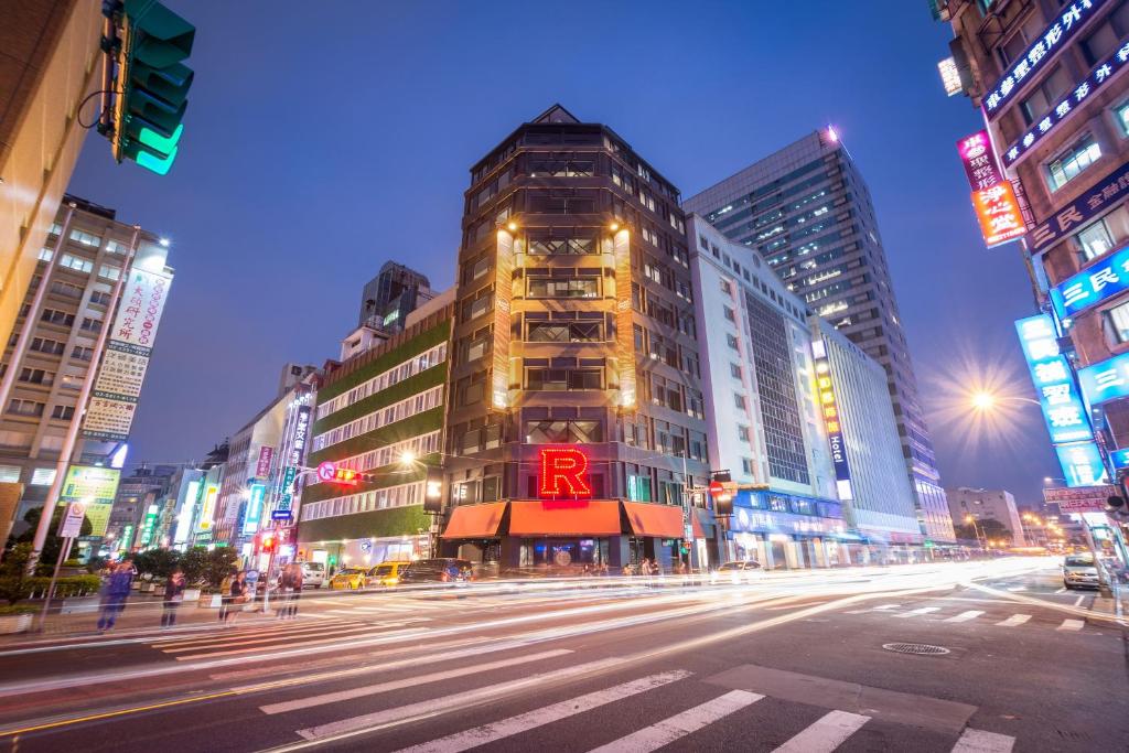 una strada di città di notte con un grande edificio di Hotel Relax 5 a Taipei