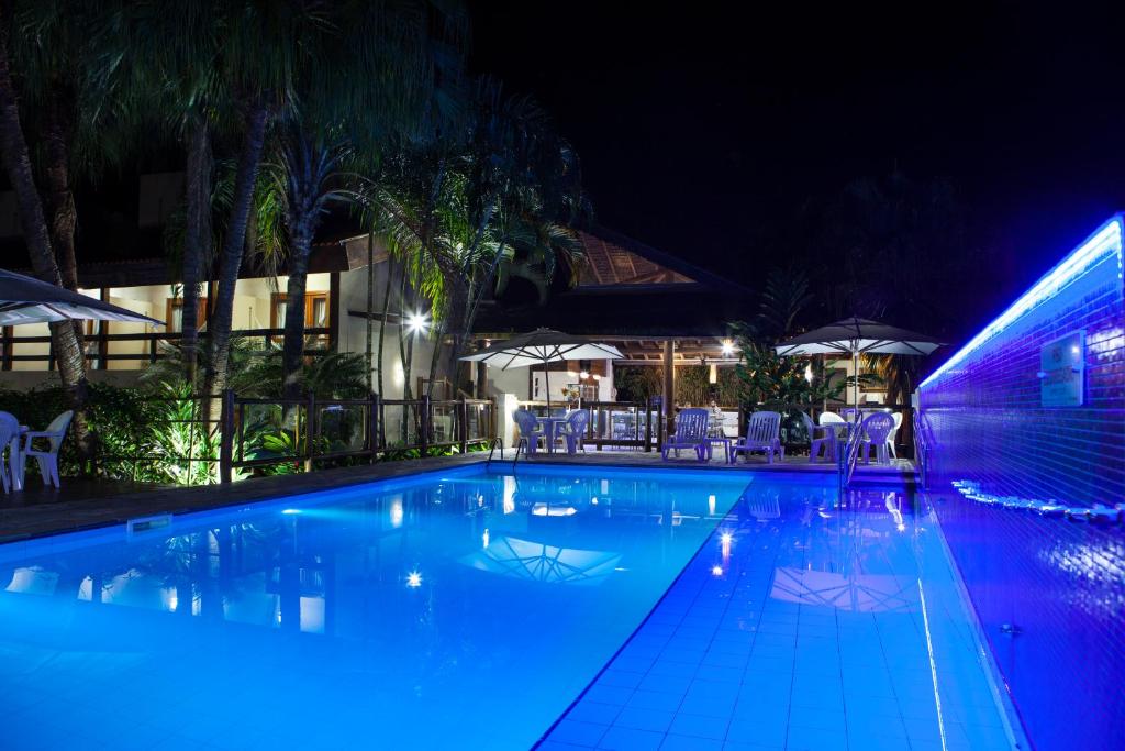 - une piscine avec des lumières bleues la nuit dans l'établissement Pousada Sol e Mar, à Juqueí