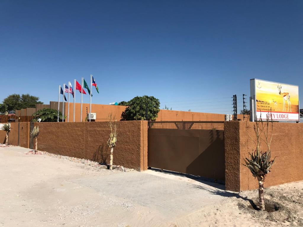 una recinzione di mattoni con bandiere di fronte a un edificio di City Lodge Etosha a Omuthiya