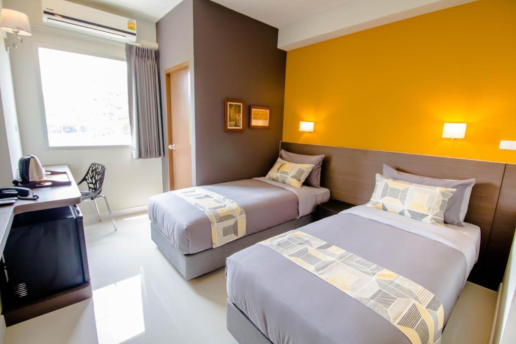 a hotel room with two beds and a television at Fortune D Hotel Loei in Loei