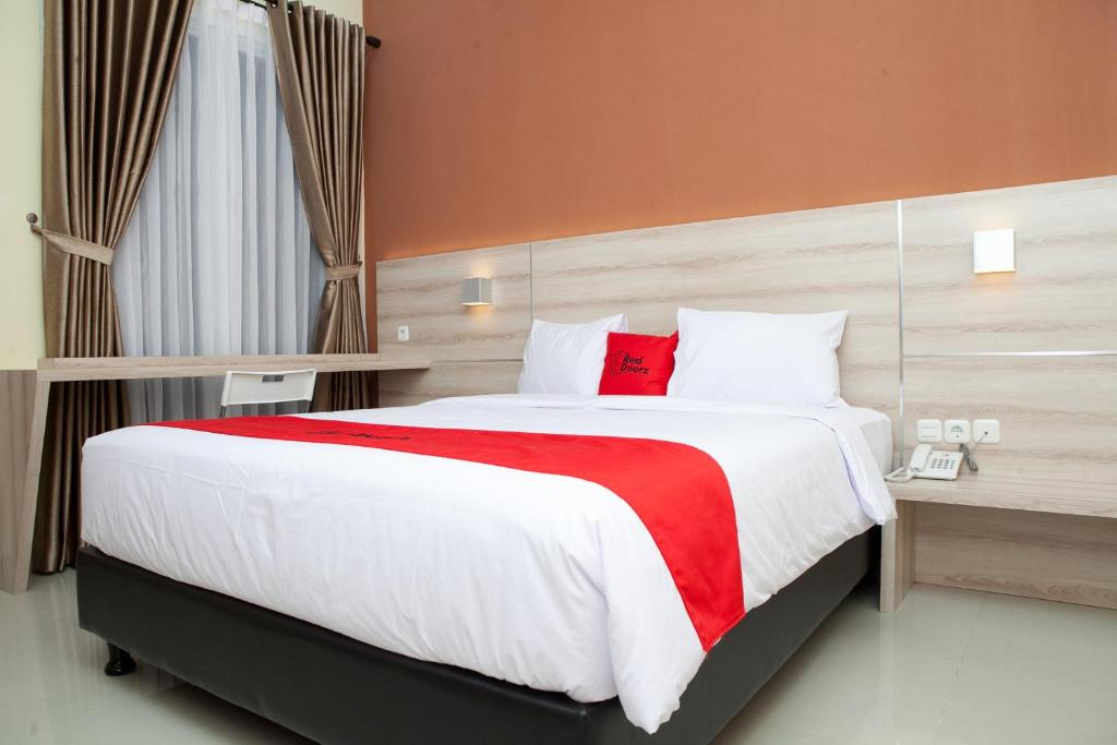 萬隆的住宿－RedDoorz Plus near Pasundan University，一间卧室配有一张带红色毯子的大床
