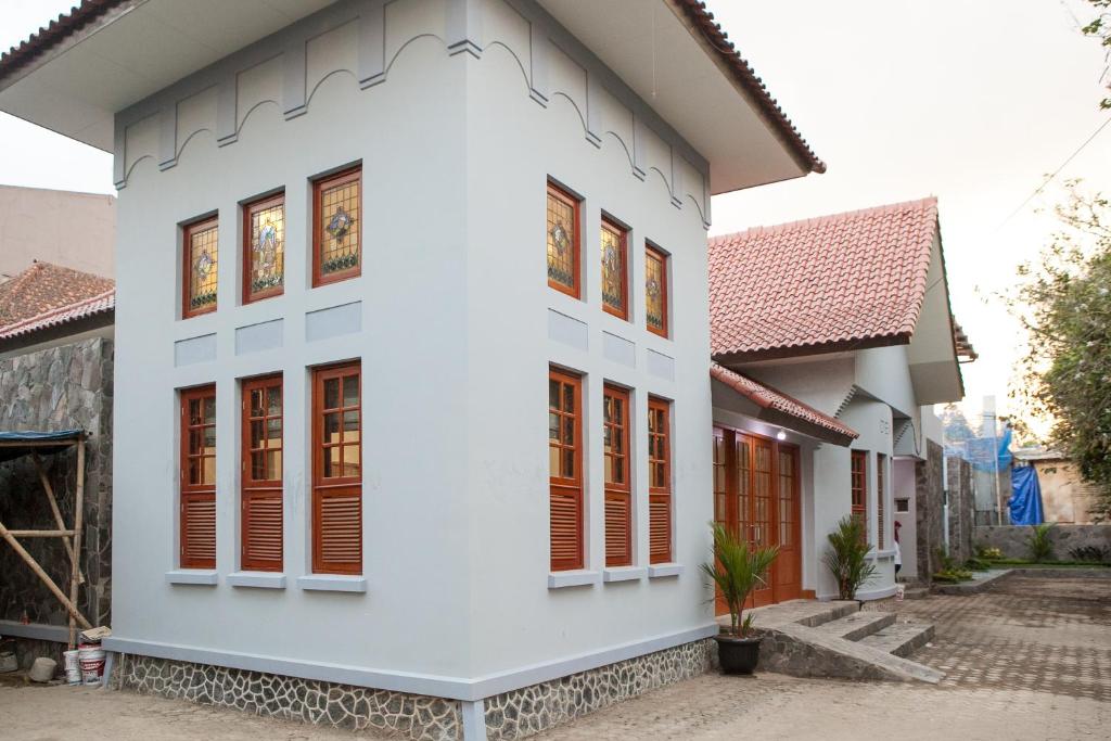 una casa bianca con finestre con persiane rosse di RedDoorz Plus near Pasundan University a Bandung