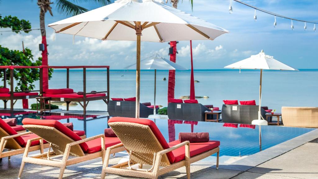 a pool with chairs and umbrellas and the ocean at Beach Republic Koh Samui in Lamai
