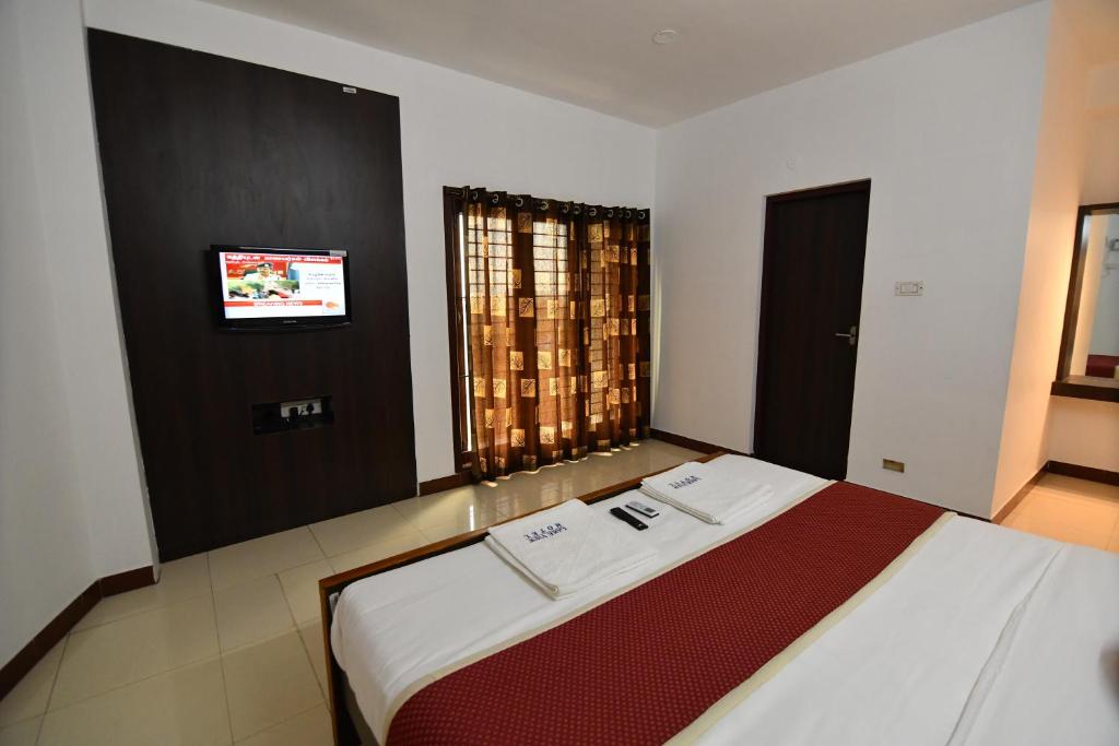 a bedroom with a large bed with a tv on the wall at Lake View Hotel in Madurai