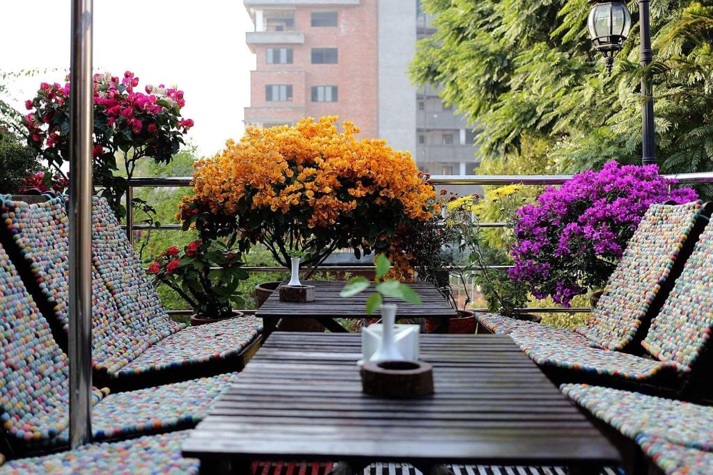 una mesa de madera con sillas y flores en el balcón en Shangri-la Boutique Hotel, en Katmandú