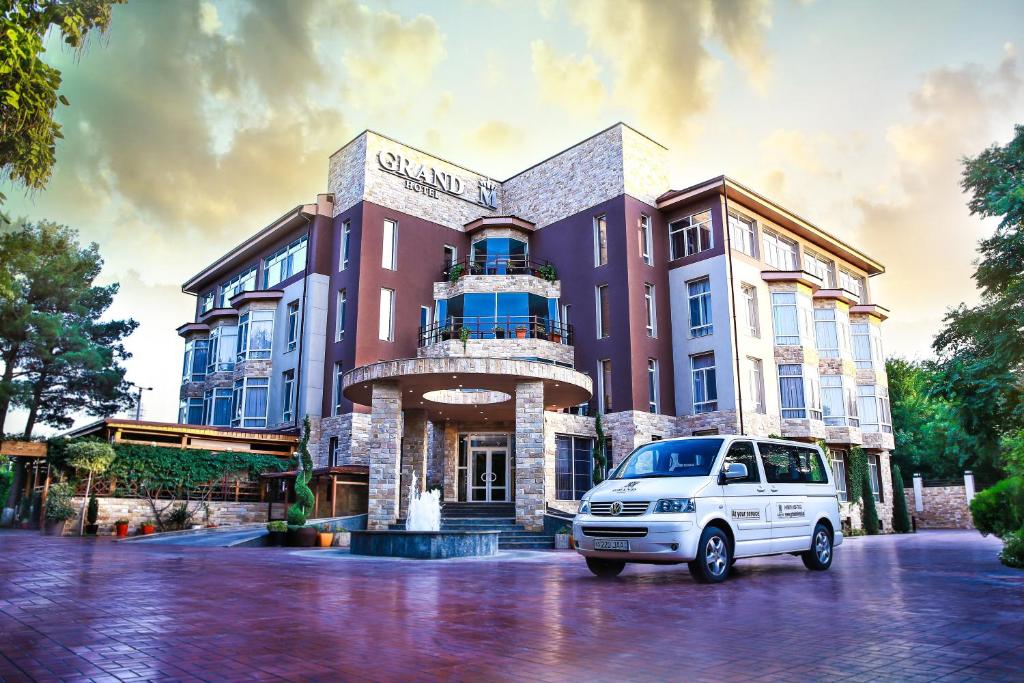 a white van parked in front of a building at Grand M Hotel in Navoi