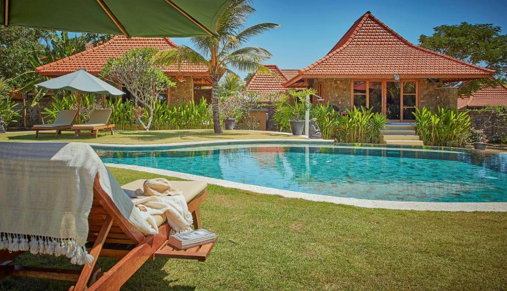 a woman laying in a chair next to a swimming pool at Three Monkeys Villas in Uluwatu