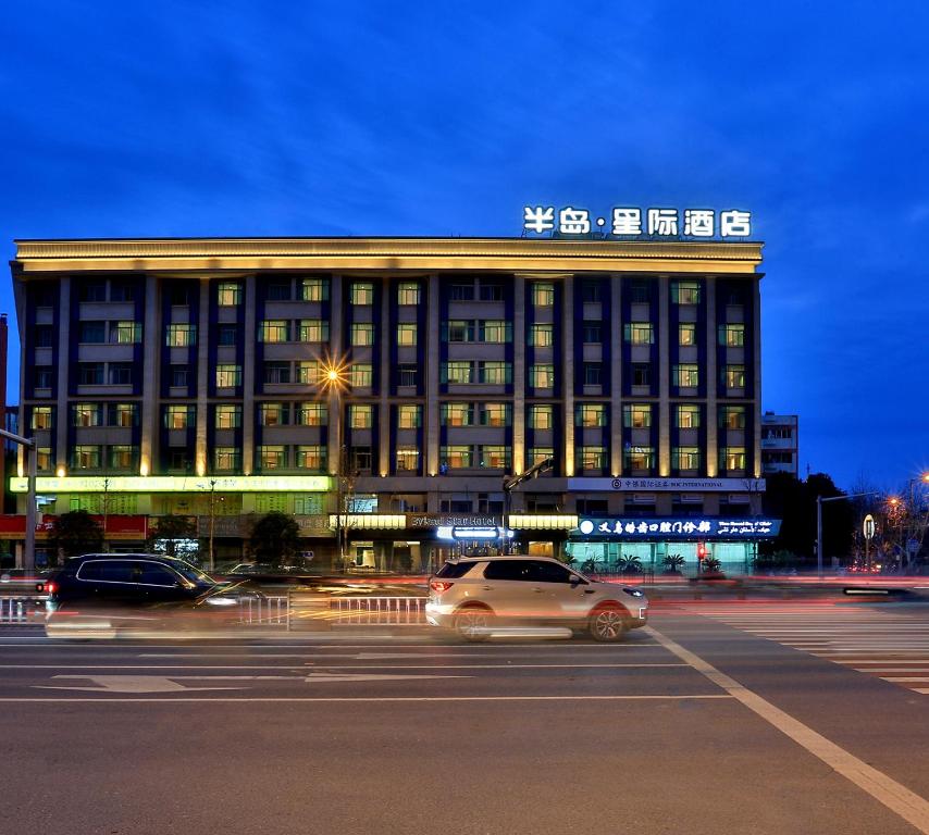 a building with a car driving in front of it at Byland Star Hotel in Yiwu