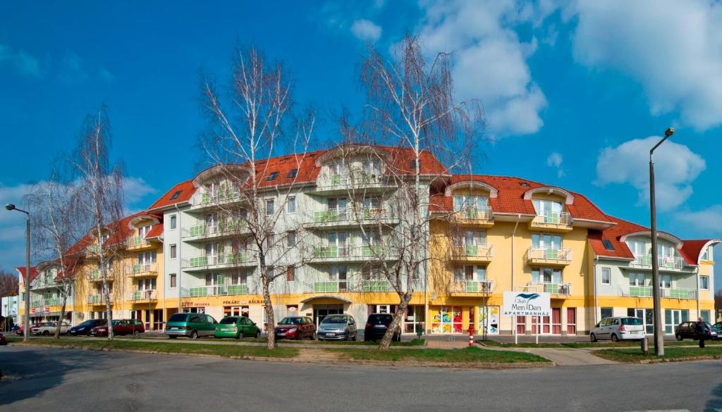 ein großes Gebäude mit davor geparkt in der Unterkunft Club MenDan Aparthotel in Zalakaros