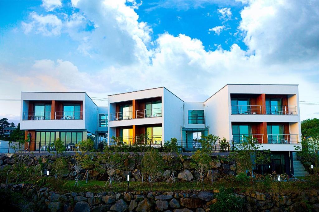 a white building with windows on top of a hill at Dorami Pension in Seogwipo