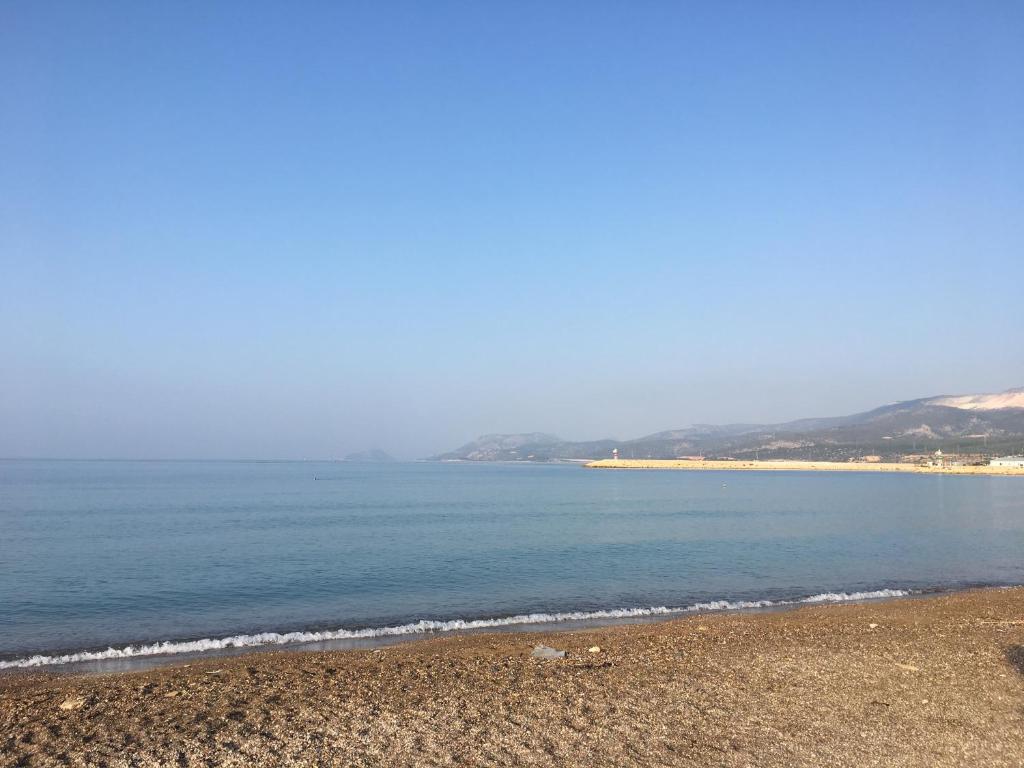 a beach with the ocean and mountains in the background at İskele Otel in Tasucu