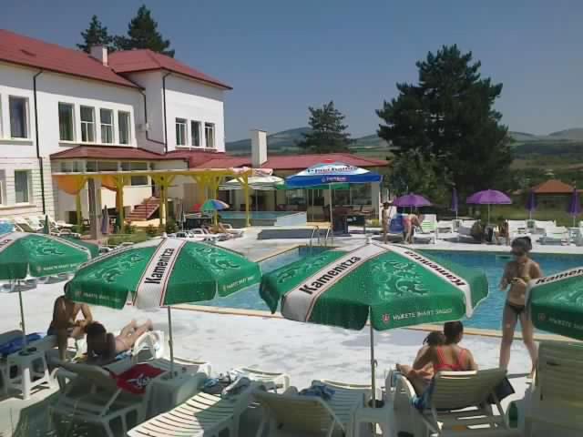 un gruppo di persone seduti intorno a una piscina con ombrelloni di Kremena Guest House a Kremena