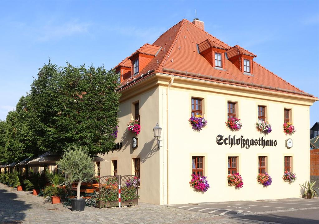 a white building with flowers on the side of it at Schlossgasthaus Lichtenwalde in Lichtenwalde