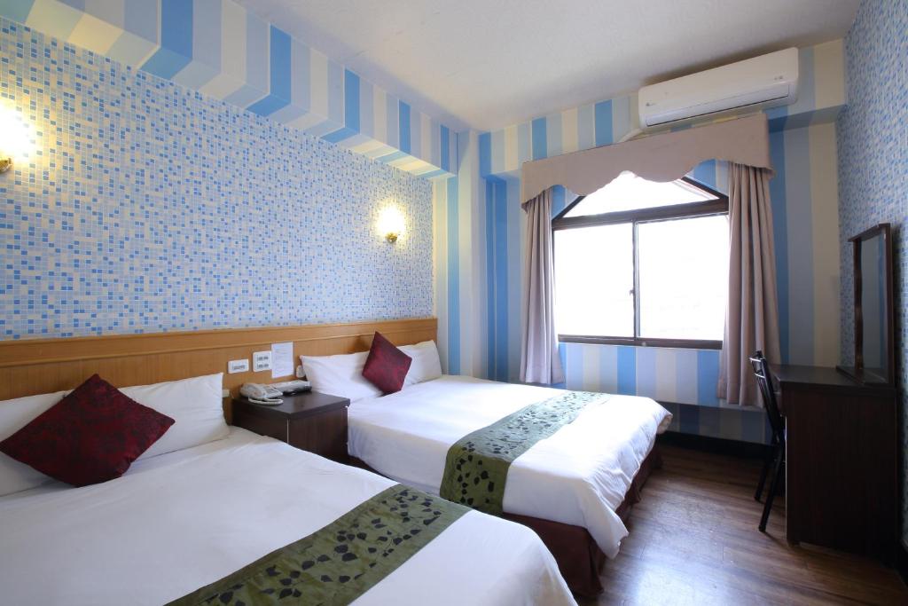 um quarto de hotel com duas camas e uma janela em Chiayi Crown Hotel em Chiayi