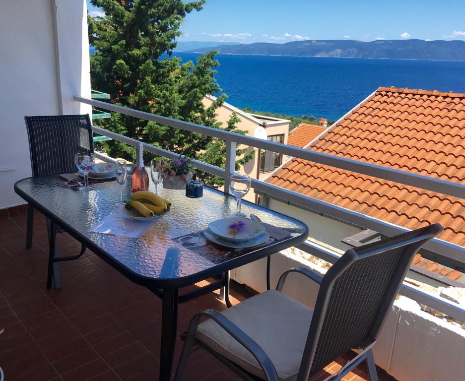 a table and chairs on a balcony with a view of the ocean at 4 Roses Apartment in Ravni