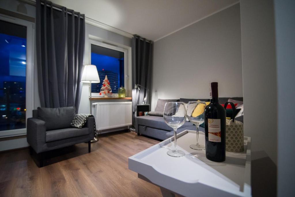 una sala de estar con una botella de vino y 2 copas de vino en Katowice City Centre Apartment, en Katowice