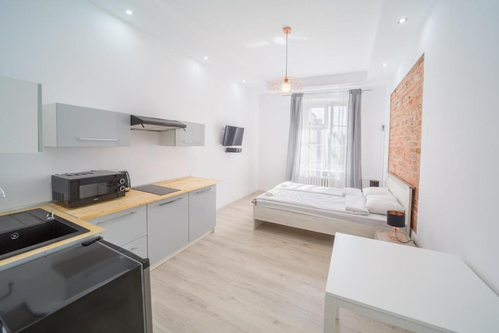a kitchen and living room with a bed in the background at White Vision Apartment in Opole