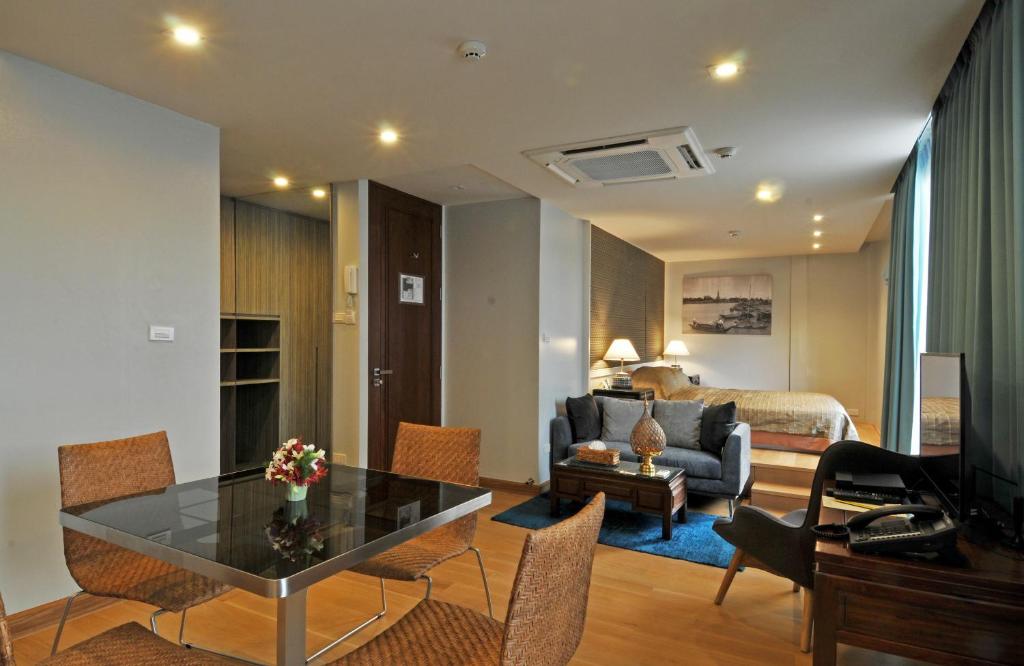uma sala de estar com uma mesa e um quarto com uma cama em Chakrabongse Residences em Banguecoque