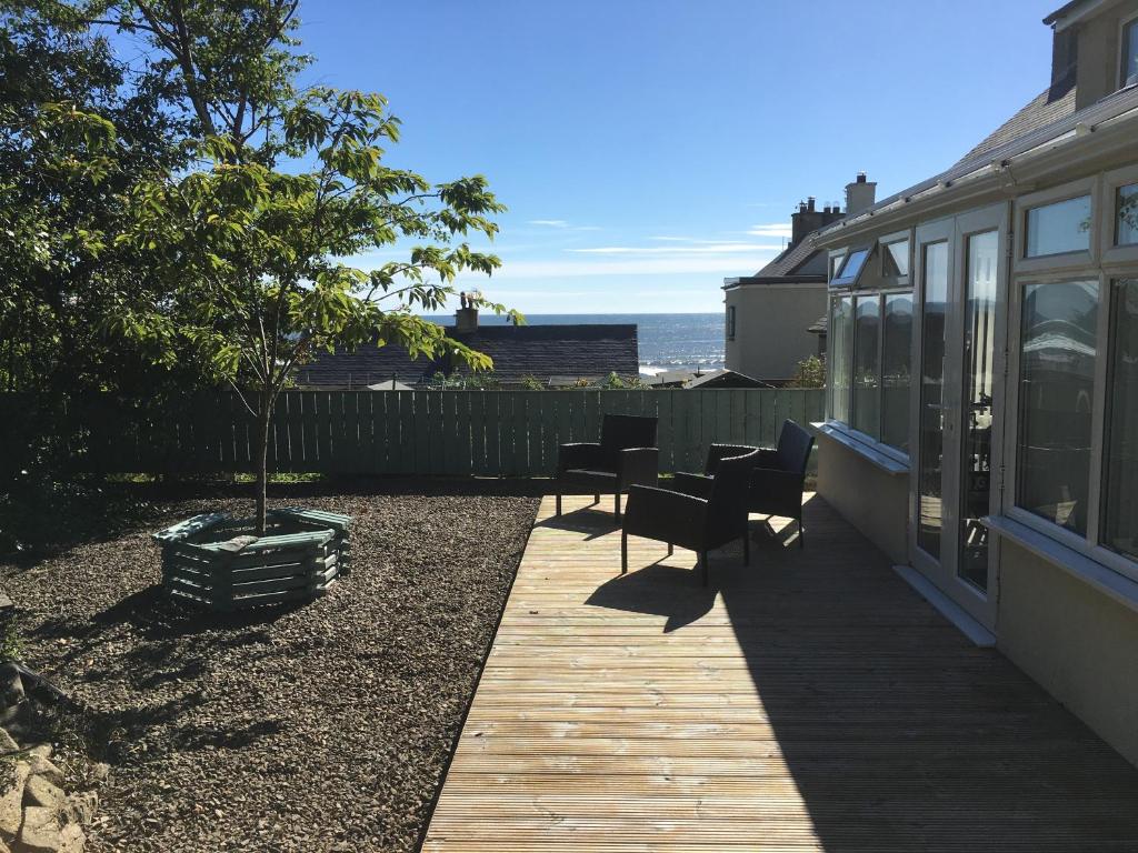 a patio with chairs and a tree next to a house at Craster Crew House in Craster