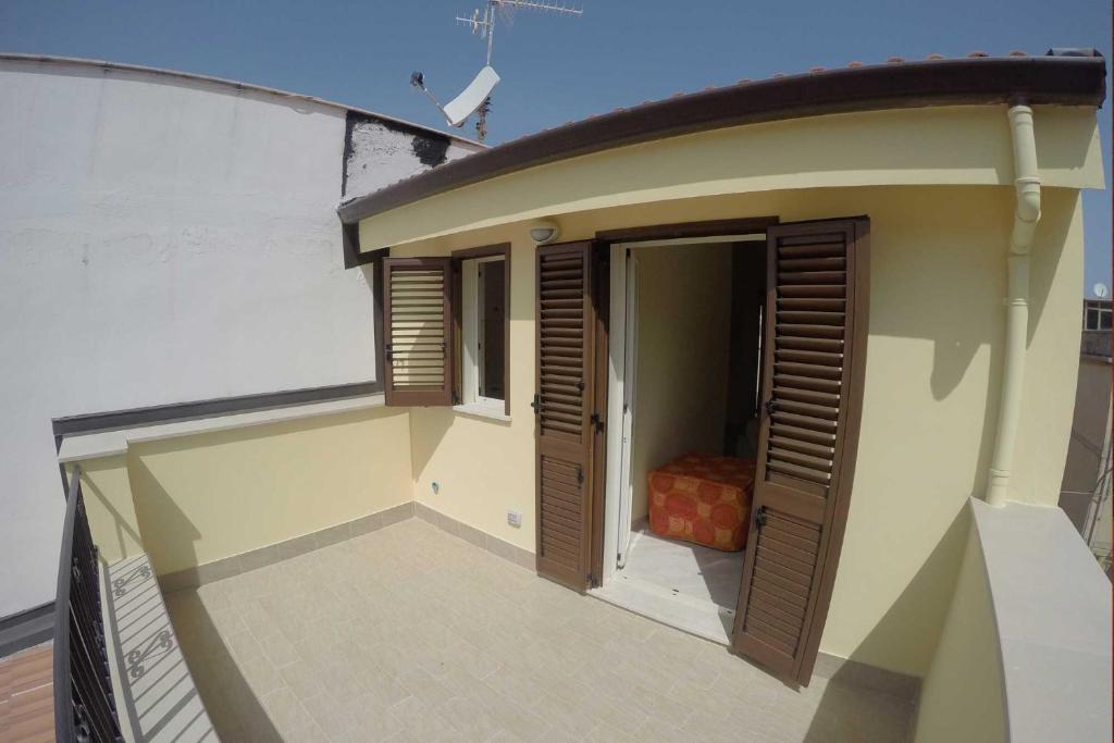 a small balcony of a house with wooden doors at BB Aretè in Scilla